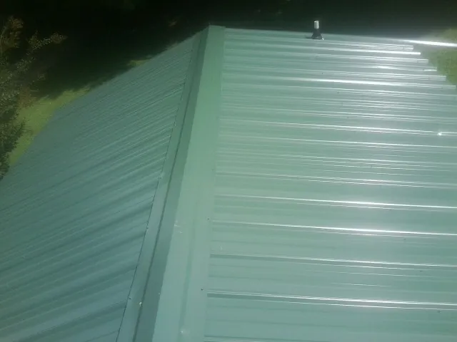 New green metal panels meeting at the ridge of a roof — Flat Roof Repair work by our crew in Zenda