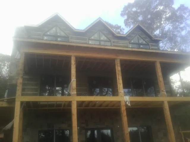Dormers and porch framing on a large log home under construction — Roof Coating work by our crew in Zenda