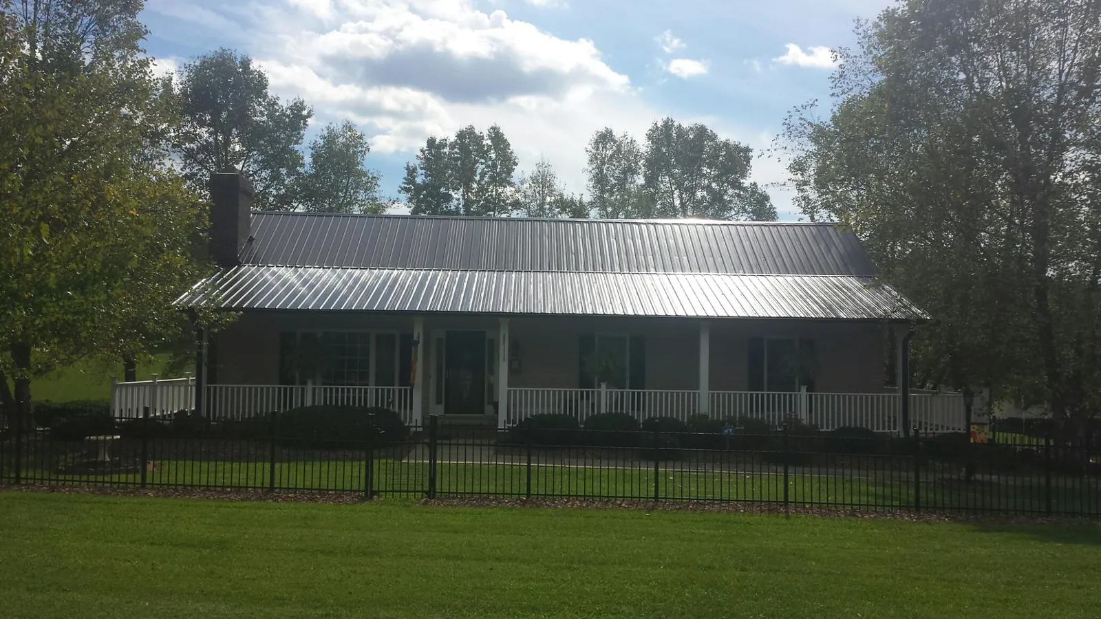Gray metal roof on a brick ranch with a full width front porch — Gutter Guard Installation work by our crew in Zenda