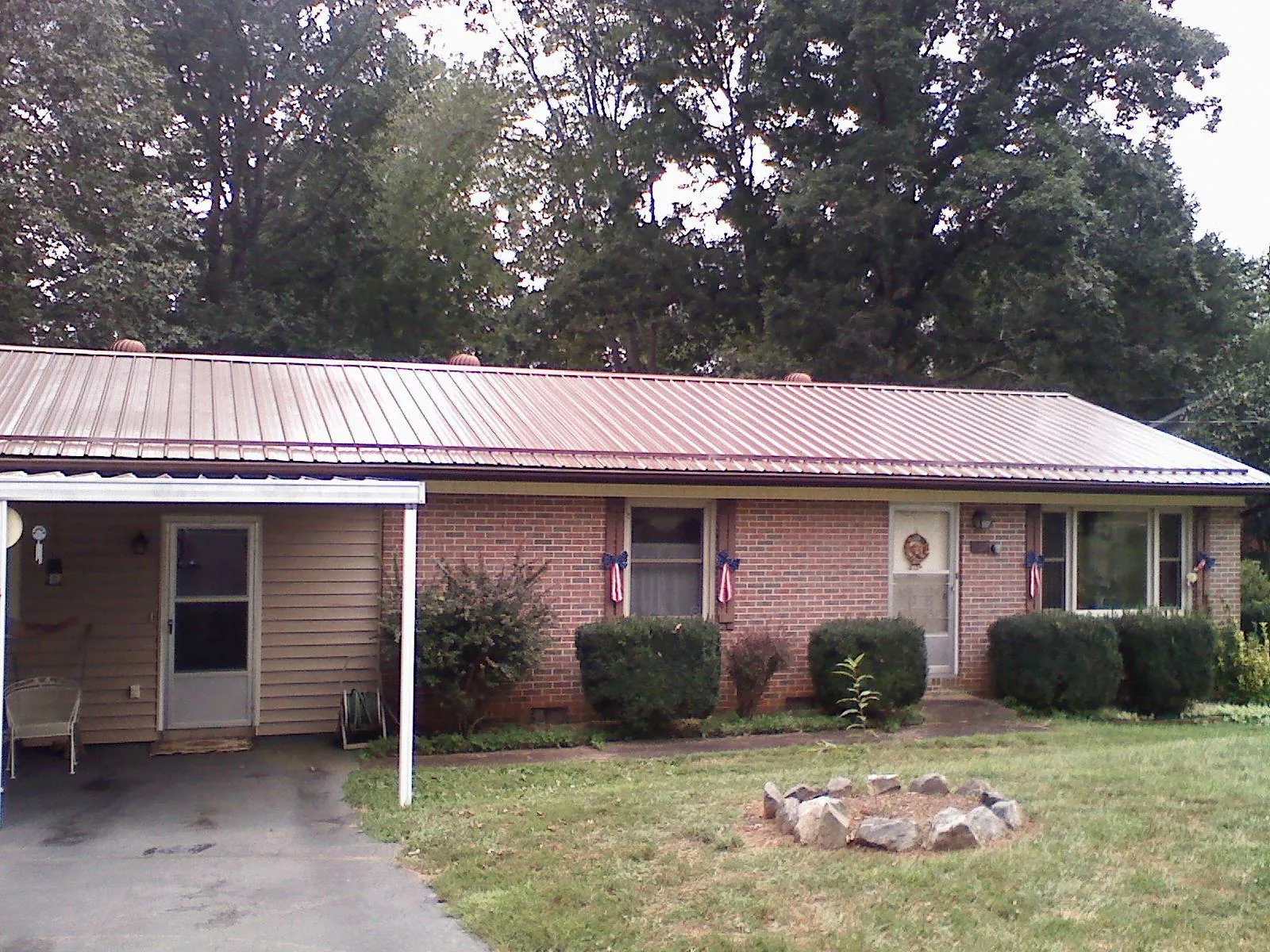Bronze metal roof and carport on a brick ranch home — Roof Repair work by our crew in Zenda