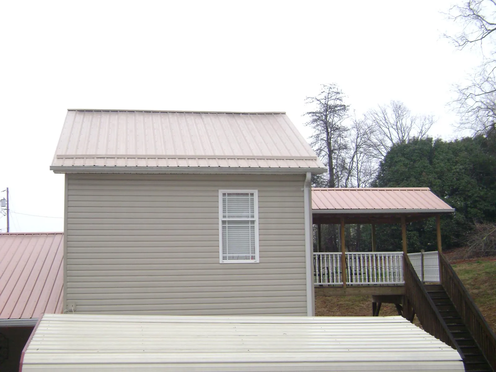 Tan metal roofs on a two story addition and attached porch, from a Roof Replacement job in Zenda