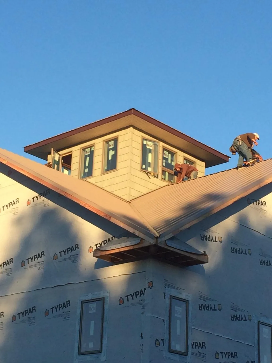 Roofers working around a rooftop cupola on a new metal roof at sunset — Roof Waterproofing in Zenda by Roofing Brothers